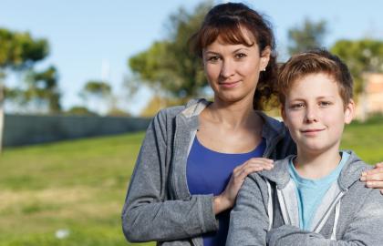 Woman and foster son smiling while standing in a park