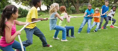 Group of kids play tug of war in a park