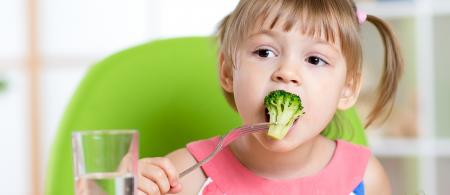 A young girl eating vegetables