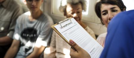 Healthcare provider holding clip board in crowded waiting room