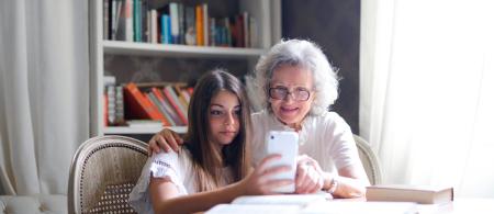An older woman and a teenager look at a cell phone