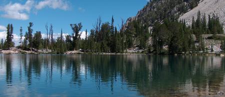 beautiful lake with blue skies and evergreens along the bank.