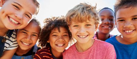 diverse group of kids looking into a camera while huddled close together