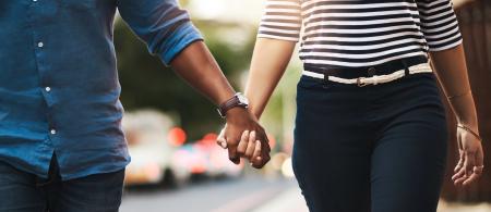 Couple holding hands and walking down the side of a street