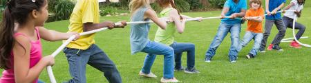 Group of kids play tug of war in a park