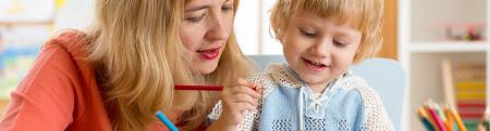 Childcare worker using colored pencils with toddler