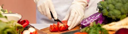 women in rubber gloves cutting vegetables