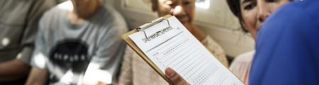 Healthcare provider holding clip board in crowded waiting room