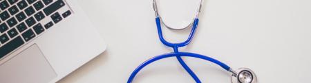 A stethoscope next to a laptop computer