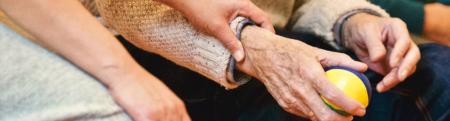 An adult helps an elderly person holding a ball