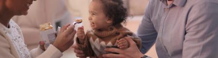 A baby being fed by two adults