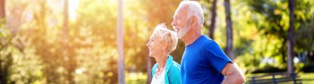 An older couple running outside in a park 
