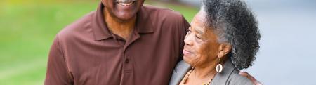 Two older adults smile and walk outside