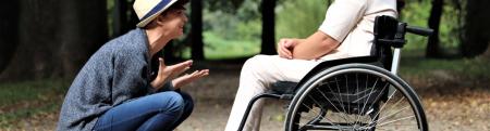 Two adults, one sitting in a wheelchair, laughing together outside