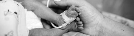 Black and white photo of a young baby's feet being held in mother's hands