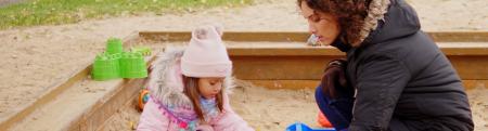 Mother playing with daughter in sandbox