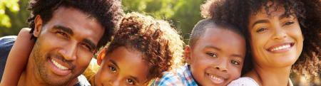 Young African American family with two children each one on their parent's back