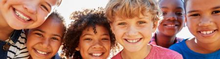 diverse group of kids looking into a camera while huddled close together