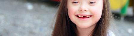 Beautiful downs syndrome girl at a carnival smiling