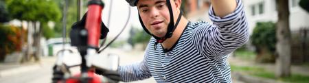 Young man kneeling down to check out his bicycle tire.