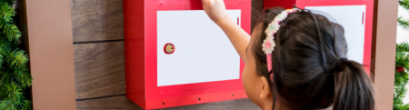 Young asian girl putting mail in a red mailbox.