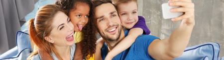 Young diverse family smiling and sitting on a sofa taking a selfie with their cell phone.