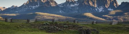 image of rural area in Idaho with a stream and grassy field with mountain backdrop