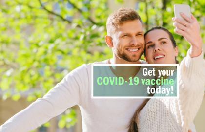 Young couple takes selfie with words superimposed Get your COVID-19 vaccine today