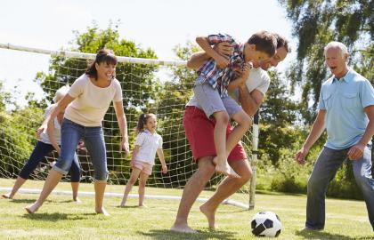 Multigenerational family playing soccer in a park together
