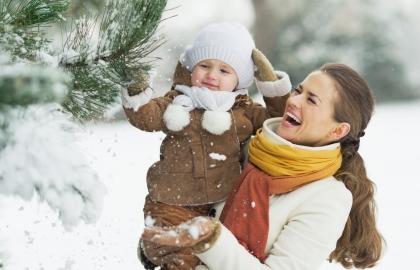 Laughing woman holding baby in snowy forest