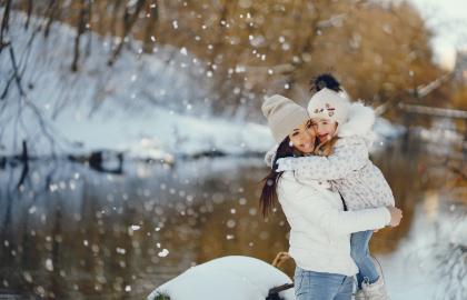 Mother and young daughter next to lake on snowy winter day