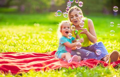 Mother and daughter playing with bubbles in grass
