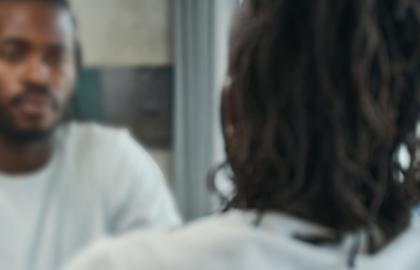 African American man looking at himself in a blurred mirror
