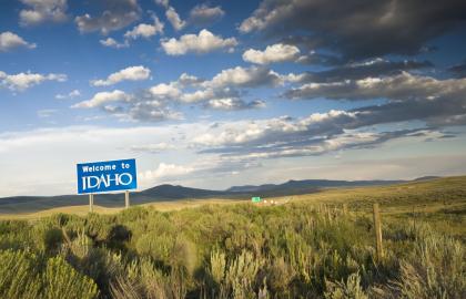 Photo of Welcome to Idaho sign standing along highway in desert
