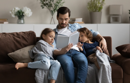 Man sitting on couch reading to two children