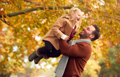 Father and young daughter having fun in a park in autumn