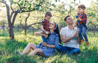 Happy family with two young boys sitting in a grassy park in spring