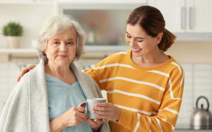 Daughter and daughter caregiver having coffee in the kitchen.