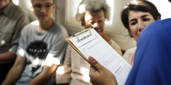 Healthcare provider holding clip board in crowded waiting room