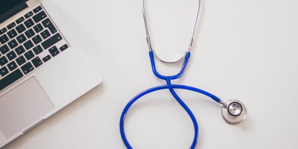 A stethoscope next to a laptop computer