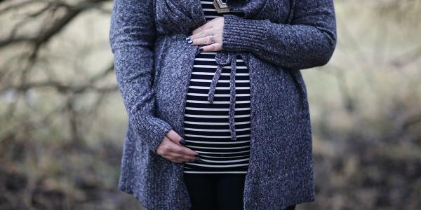 Pregnant woman in a striped shirt stands outside