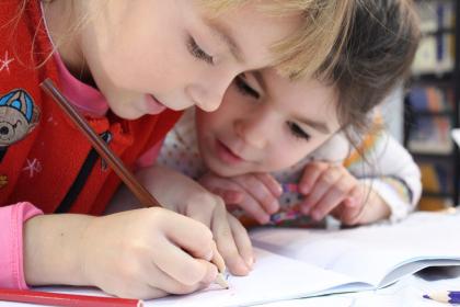 Two children leaning over a workbook
