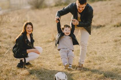 A could play soccer in a field with a happy toddler.