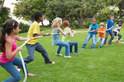 Group of kids play tug of war in a park