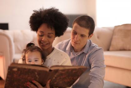 Two adults read with a young child
