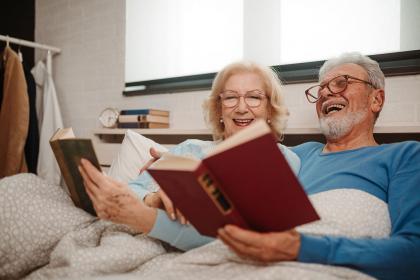 An older couple reading books in bed