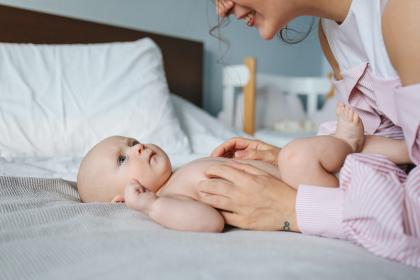 Adult plays with a baby on a bed