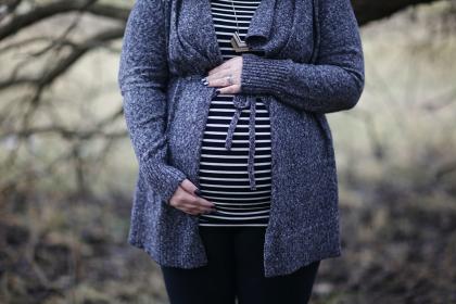 Pregnant woman in a striped shirt stands outside