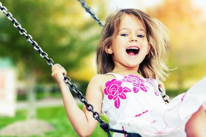 Happy girl playing on a swingset