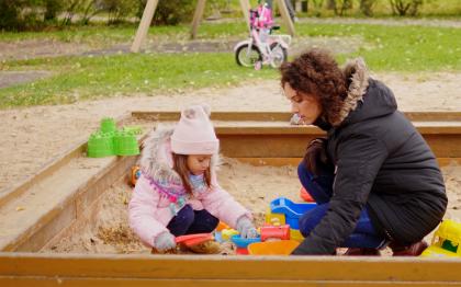 Mother playing with daughter in sandbox